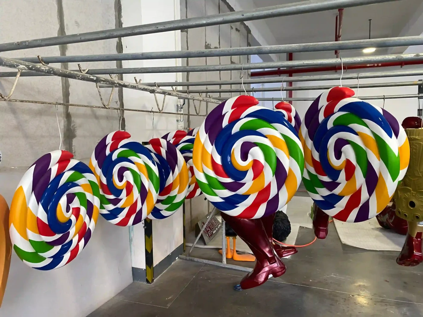 giant candy swirl christmas display props in rainbow colours staged in production facility
